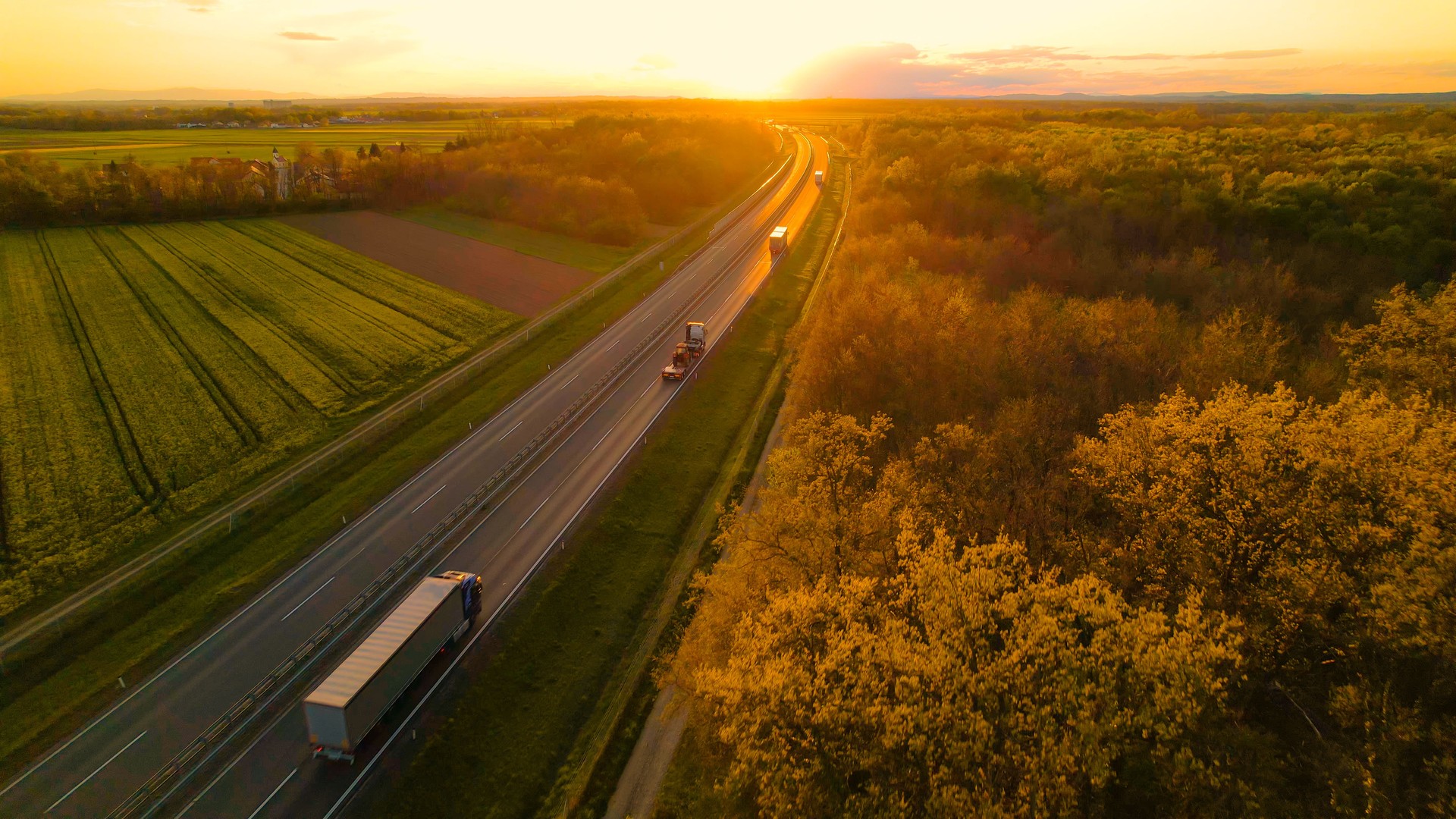 AERIAL Convoy of cargo trucks on a countryside highway in beautiful golden light